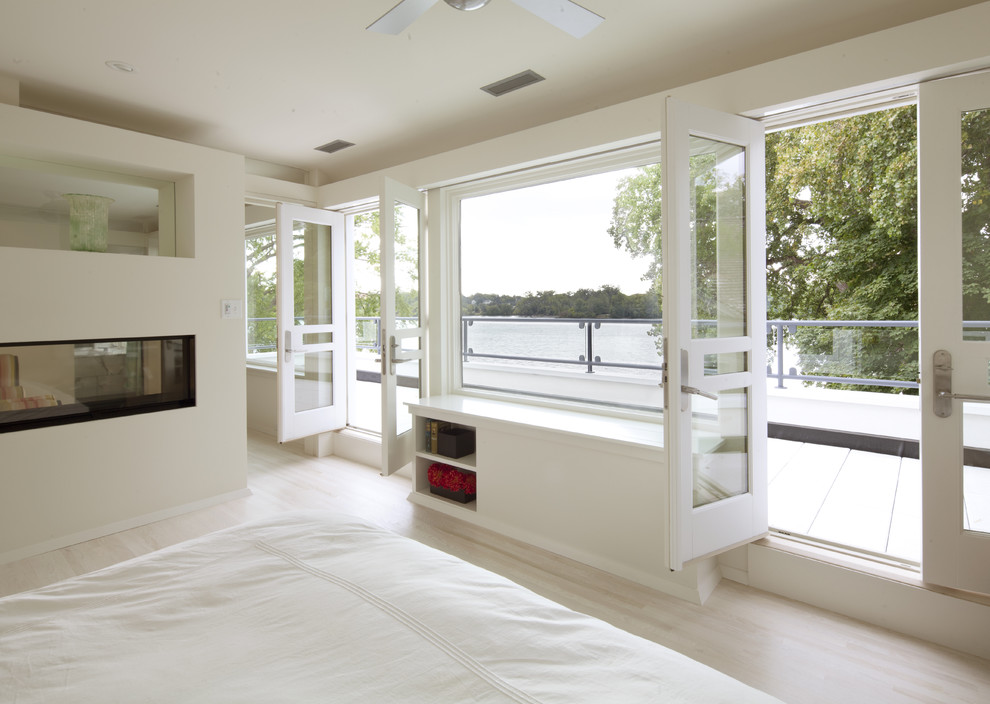 Exempel på ett modernt sovrum, med beige väggar, ljust trägolv och en dubbelsidig öppen spis