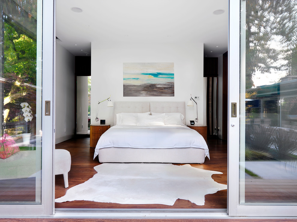 Inspiration pour une chambre parentale minimaliste de taille moyenne avec aucune cheminée, un mur blanc et un sol en bois brun.