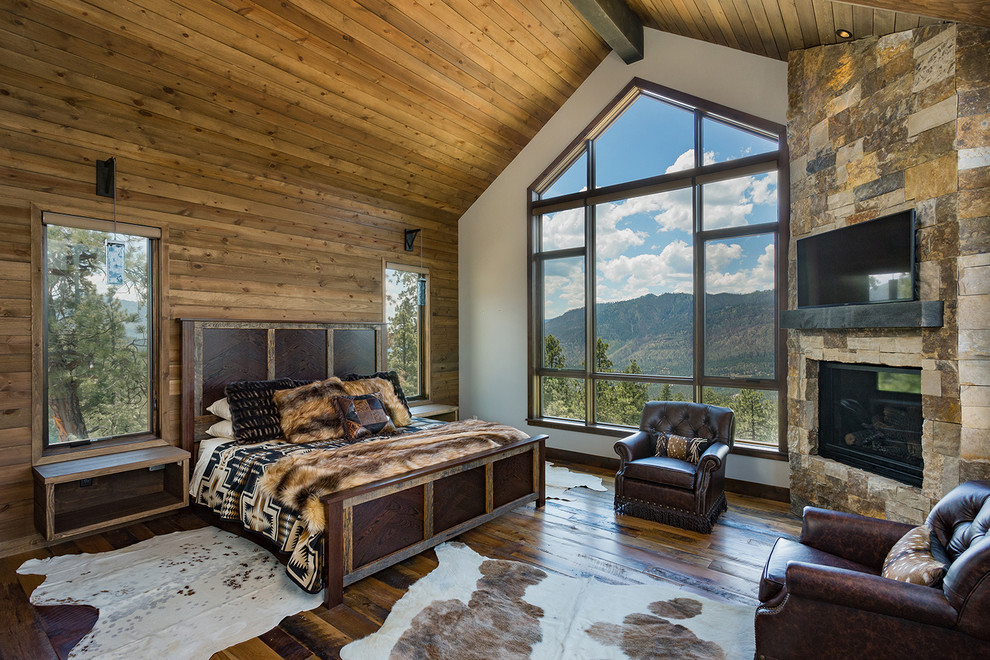 Design ideas for a large rustic master bedroom in Denver with medium hardwood flooring, a corner fireplace, a stone fireplace surround and white walls.