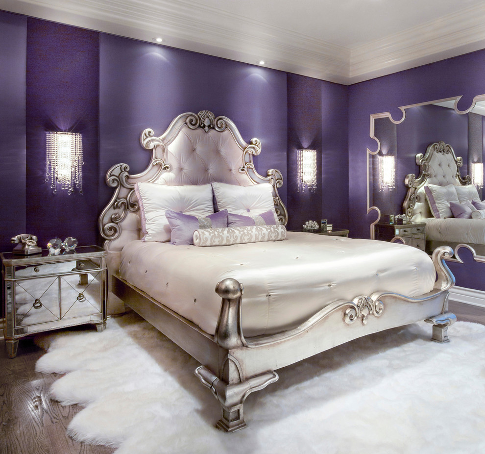 Imagen de dormitorio principal tradicional renovado de tamaño medio sin chimenea con paredes púrpuras y suelo de madera en tonos medios