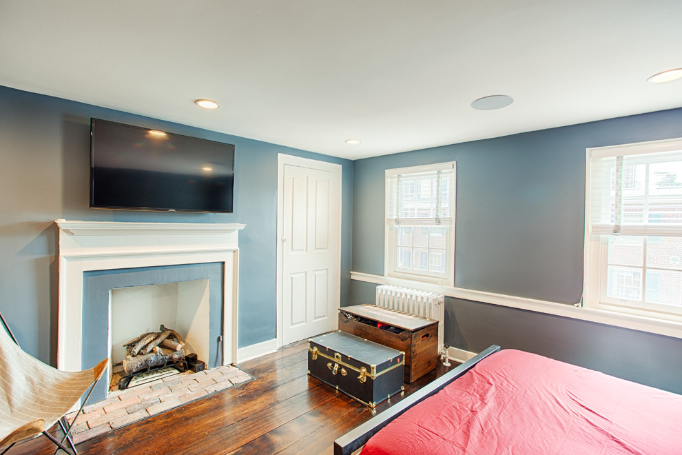 Inspiration pour une chambre d'amis design de taille moyenne avec un mur bleu, parquet foncé, une cheminée standard et un manteau de cheminée en bois.