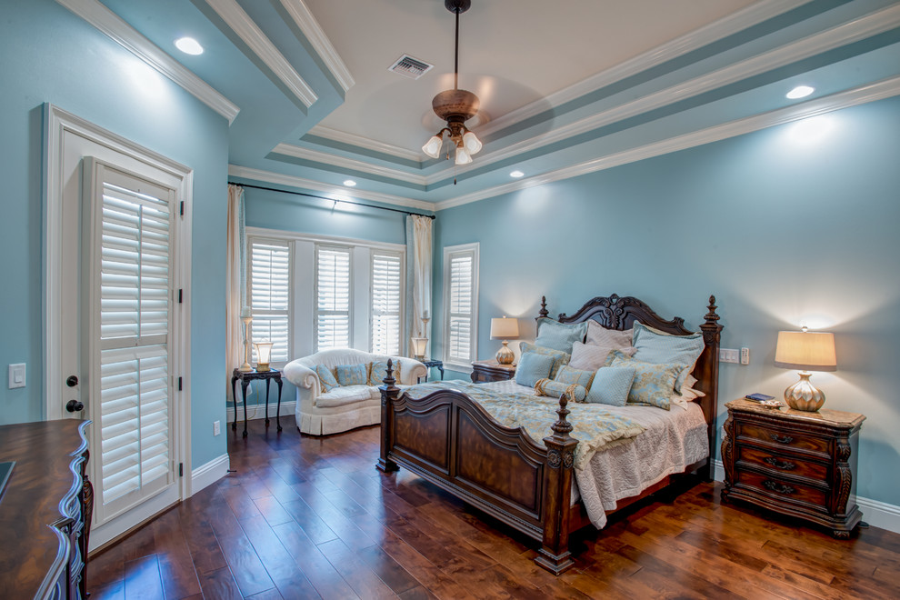 This is an example of a large classic master bedroom in Orlando with blue walls, dark hardwood flooring, no fireplace and brown floors.