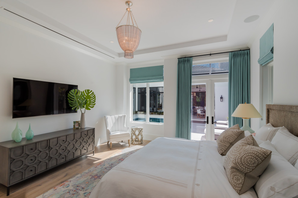 マイアミにある広いビーチスタイルのおしゃれな主寝室 (白い壁、無垢フローリング、ベージュの床) のインテリア