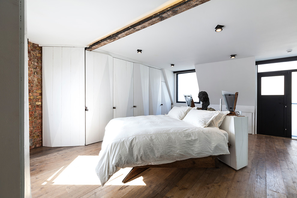Design ideas for a small industrial bedroom in London with medium hardwood flooring.