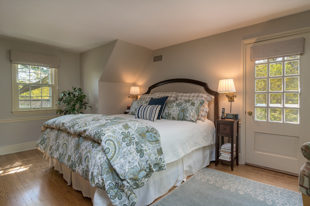 Modelo de dormitorio principal clásico de tamaño medio sin chimenea con paredes azules, suelo de madera en tonos medios y suelo marrón