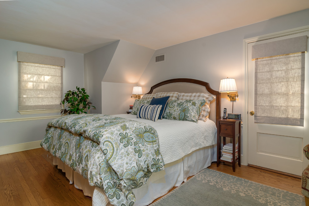 Foto de dormitorio principal tradicional de tamaño medio sin chimenea con paredes azules, suelo de madera en tonos medios y suelo marrón