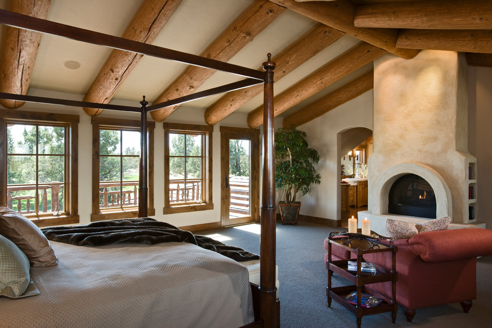 Diseño de dormitorio principal rural grande con paredes beige, moqueta, todas las chimeneas y marco de chimenea de yeso