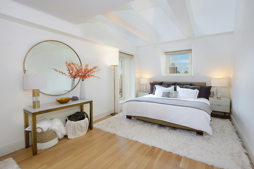 Design ideas for a contemporary bedroom in New York with white walls, medium hardwood flooring and brown floors.