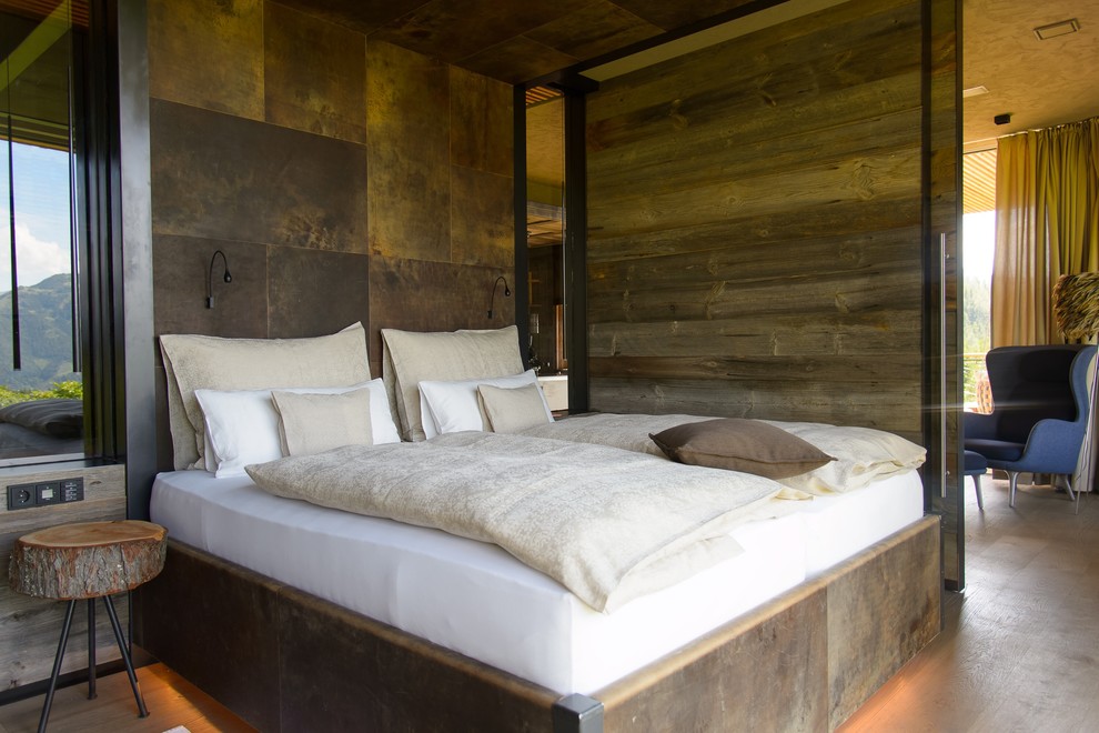 Réalisation d'une petite chambre parentale chalet avec un mur marron, un sol en bois brun et un sol marron.