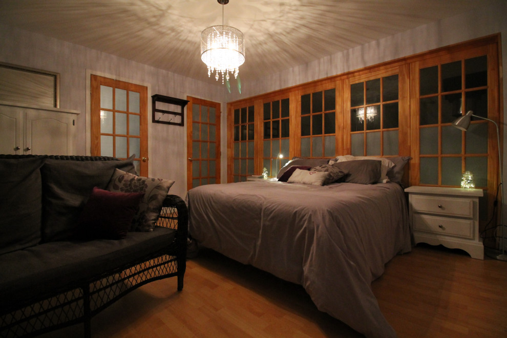 Exemple d'une chambre parentale tendance en bois de taille moyenne avec un mur gris, sol en stratifié, une cheminée standard, un manteau de cheminée en métal et un sol beige.