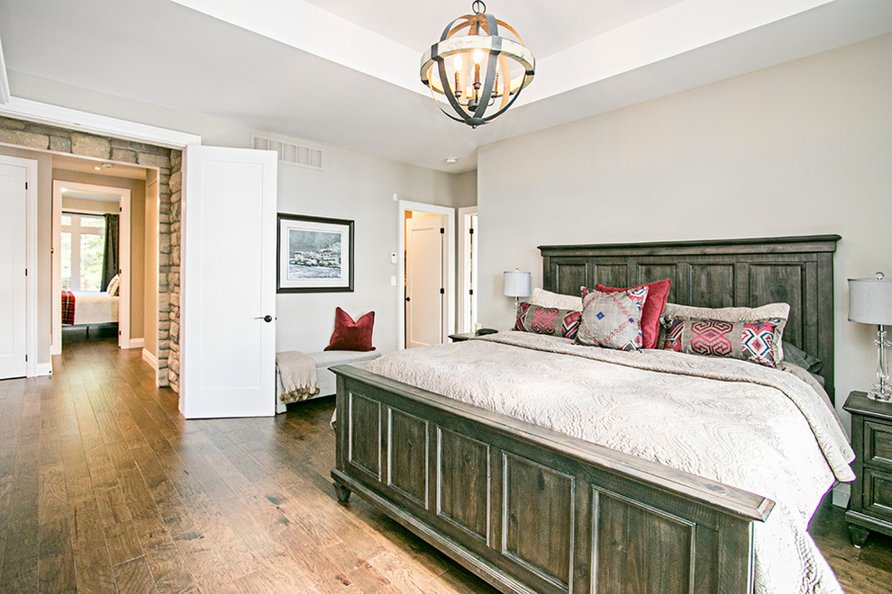 Country Hauptschlafzimmer mit weißer Wandfarbe, hellem Holzboden, Kamin, Kaminumrandung aus Stein und braunem Boden in Toronto