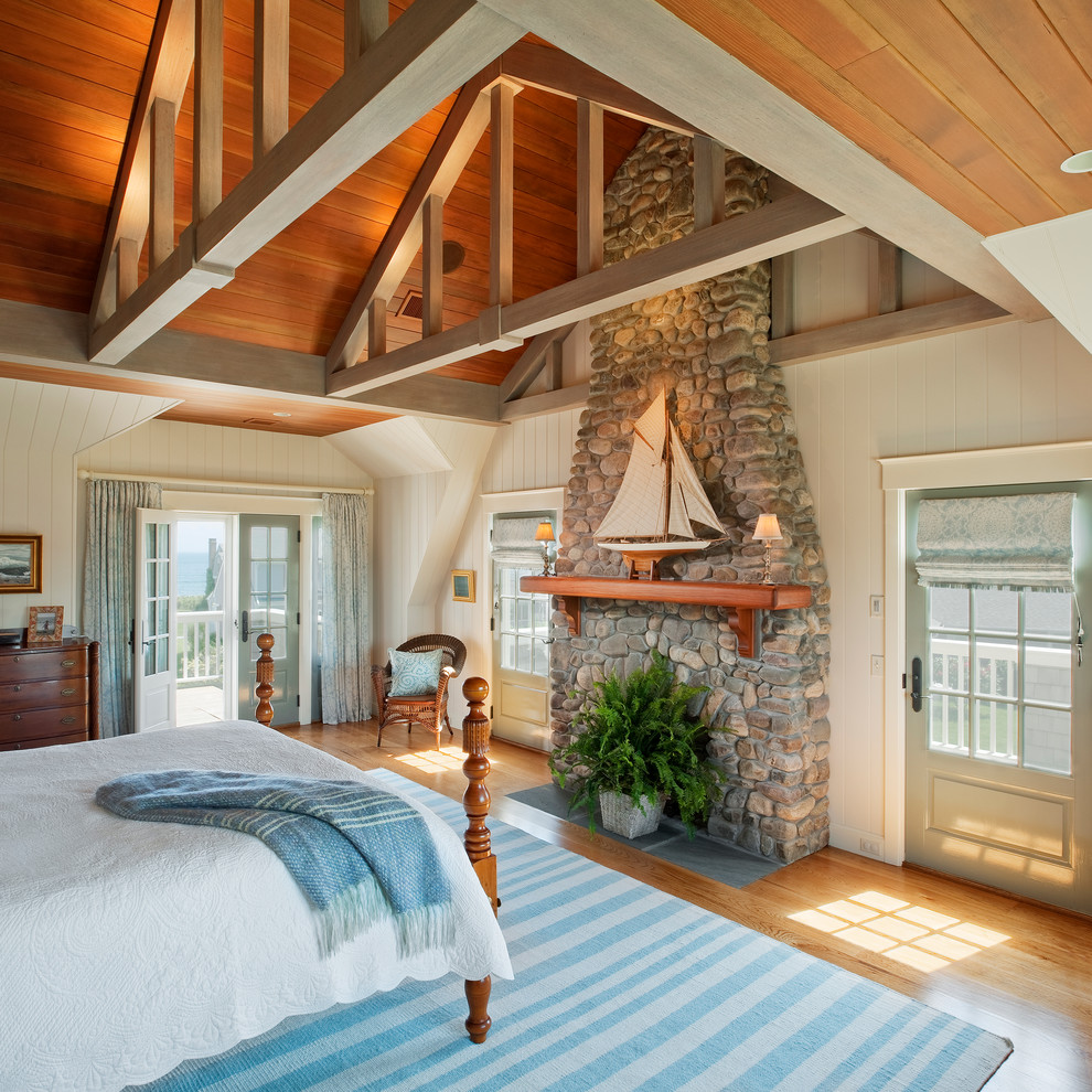 Maritimes Schlafzimmer mit weißer Wandfarbe, braunem Holzboden und Kaminumrandung aus Stein in Providence