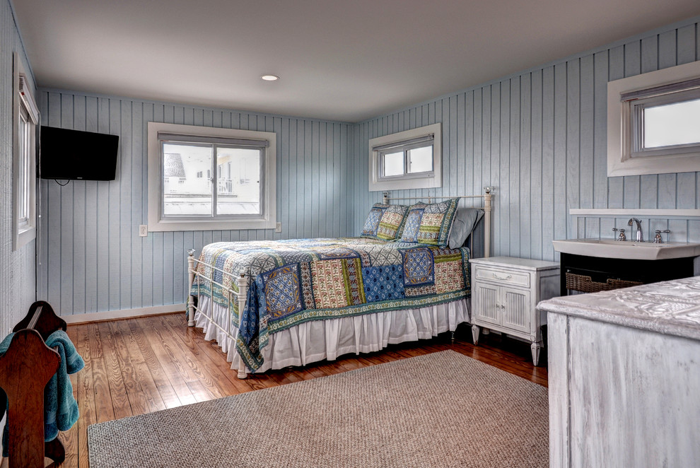 На фото: гостевая спальня среднего размера, (комната для гостей) в морском стиле с синими стенами, паркетным полом среднего тона, коричневым полом и телевизором без камина