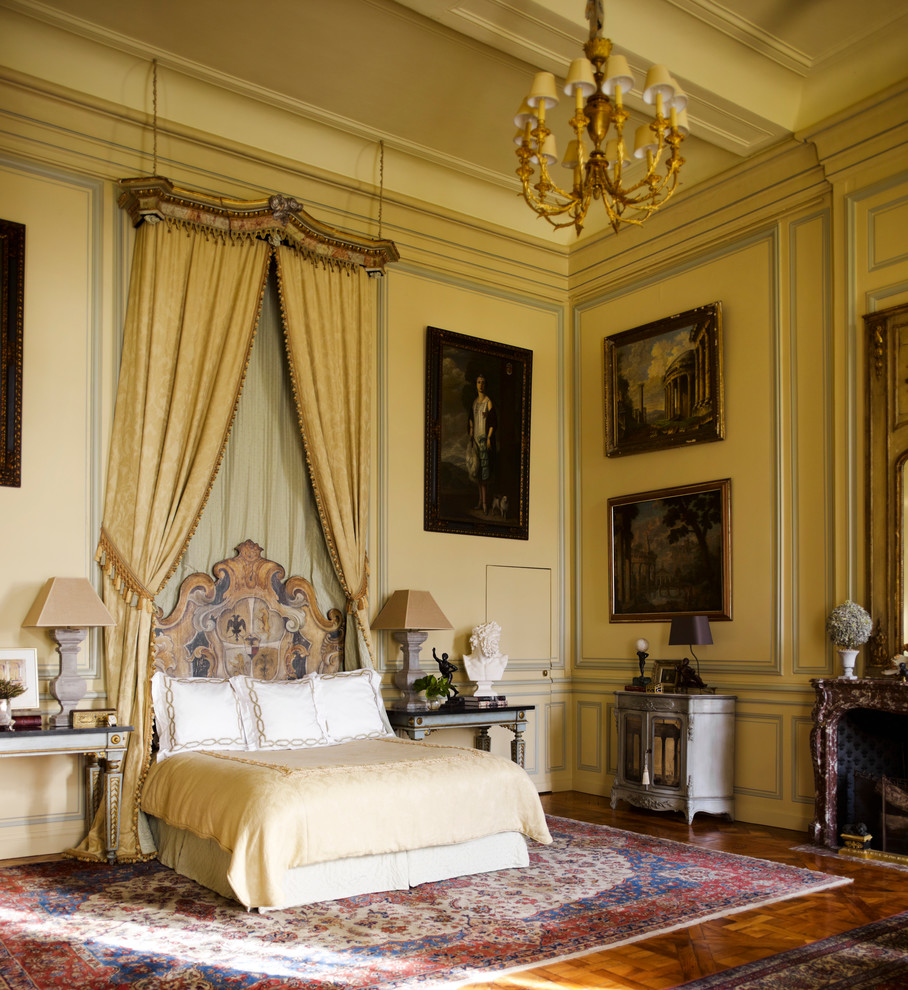 Пример оригинального дизайна: большая хозяйская спальня в классическом стиле с желтыми стенами, паркетным полом среднего тона и стандартным камином