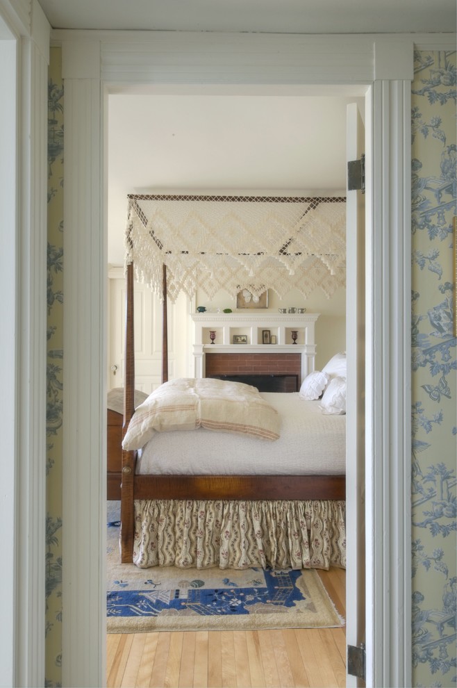Elegant light wood floor bedroom photo in Portland Maine with beige walls and a standard fireplace