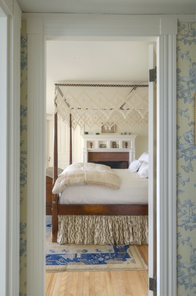 Klassisches Schlafzimmer mit beiger Wandfarbe, hellem Holzboden und Kamin in Portland Maine
