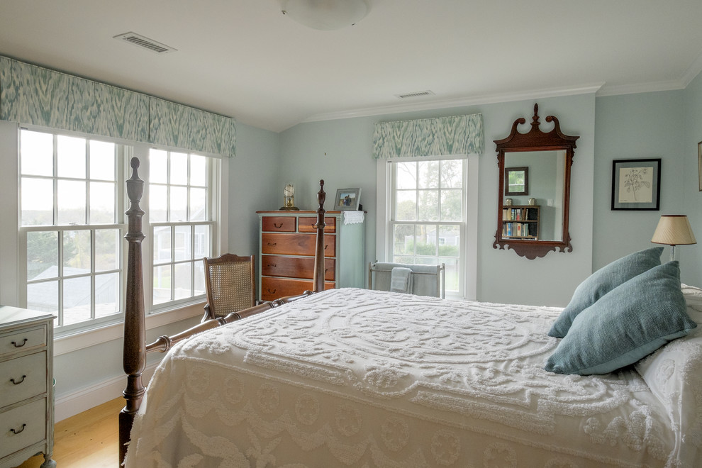 Immagine di una camera degli ospiti classica di medie dimensioni con pareti blu, pavimento in legno massello medio e nessun camino