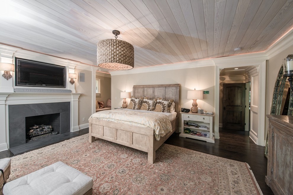 Foto de dormitorio principal costero de tamaño medio sin chimenea con paredes beige, suelo de madera oscura y marco de chimenea de piedra