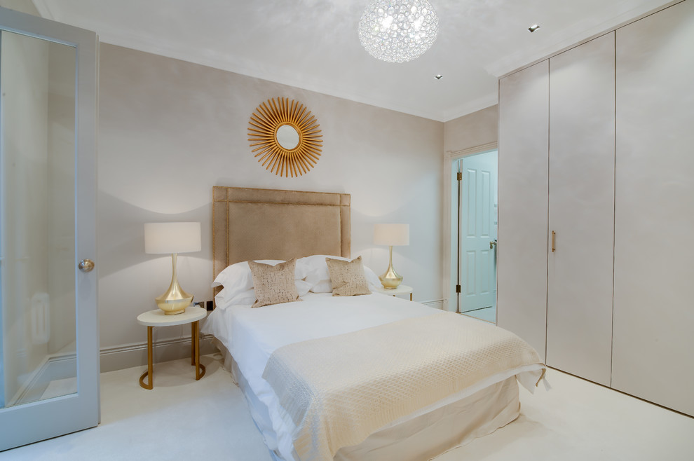 This is an example of a medium sized contemporary master bedroom in London with beige walls and carpet.