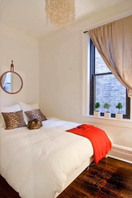 Cette photo montre une petite chambre parentale éclectique avec un mur blanc, parquet foncé et un sol marron.