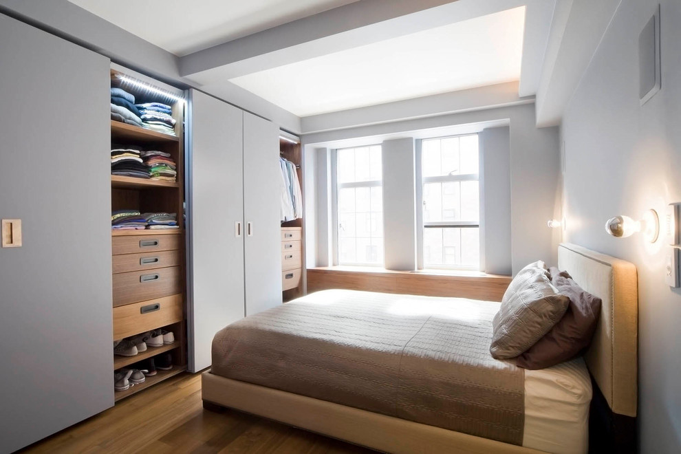 Ejemplo de habitación de invitados minimalista de tamaño medio sin chimenea con paredes grises, suelo de madera clara y suelo beige