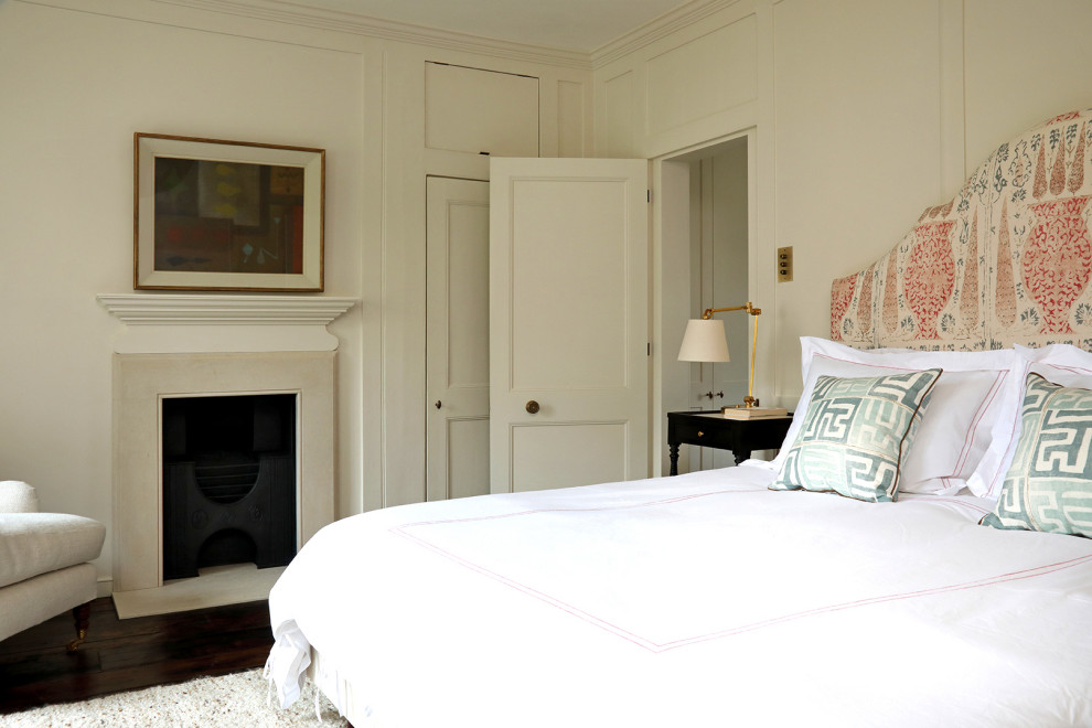 Свежая идея для дизайна: маленькая хозяйская спальня в классическом стиле с белыми стенами, деревянным полом, стандартным камином, фасадом камина из камня и коричневым полом для на участке и в саду - отличное фото интерьера