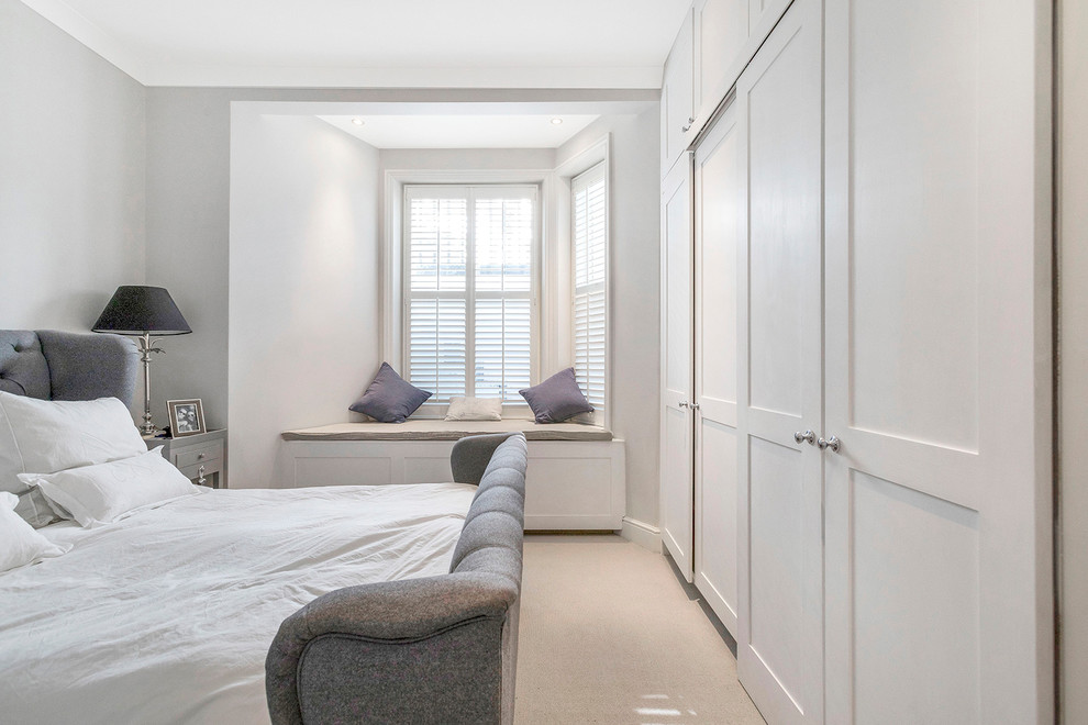 This is an example of a medium sized traditional master bedroom in London with grey walls, carpet and beige floors.