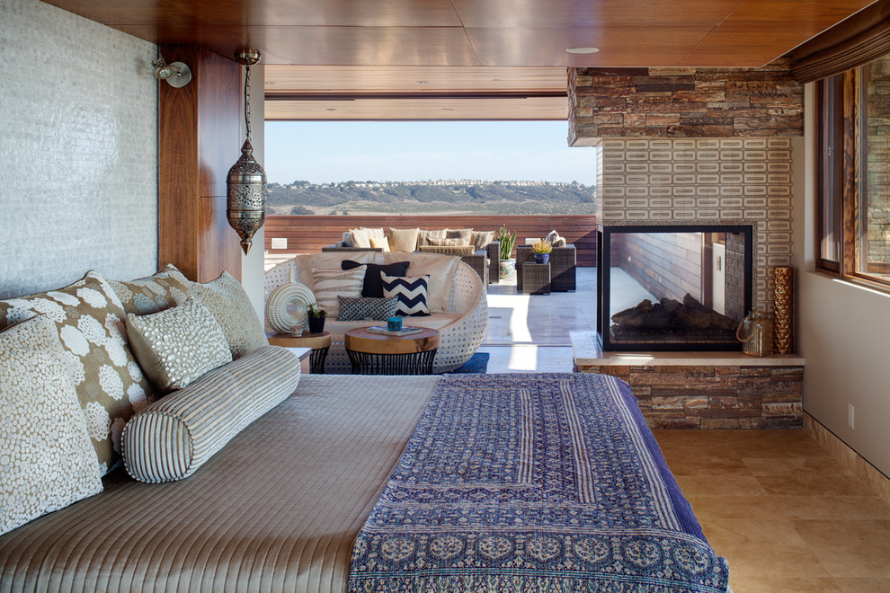 Photo of a world-inspired master bedroom in San Diego with a two-sided fireplace.