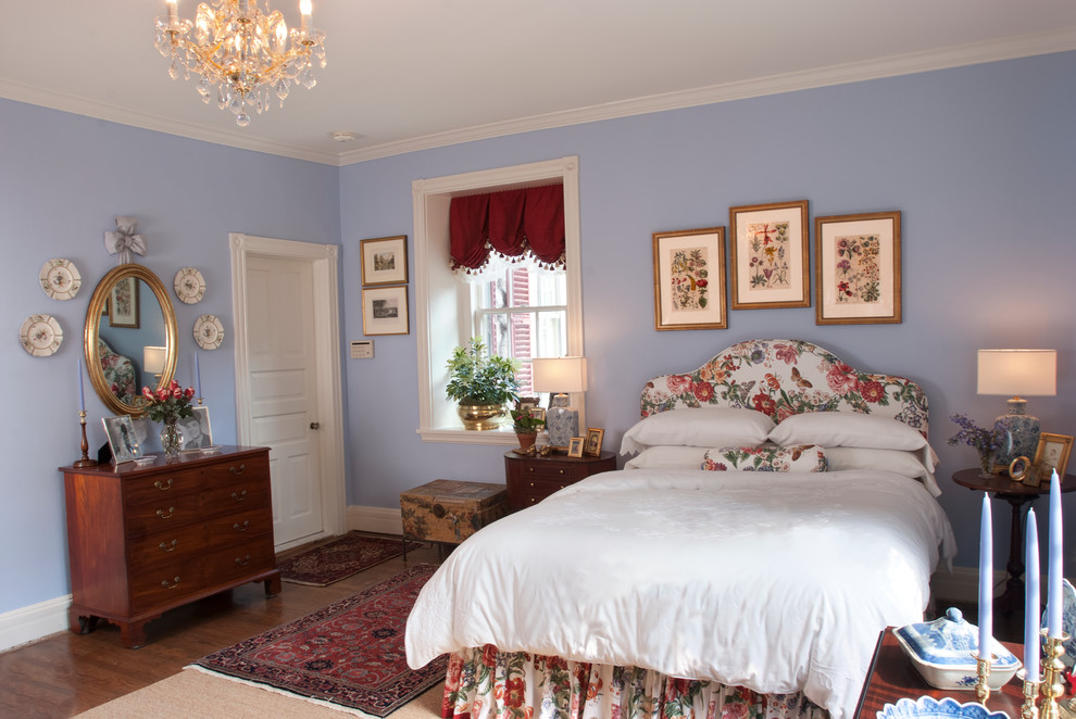 Ejemplo de dormitorio principal tradicional de tamaño medio con paredes azules y suelo de madera en tonos medios