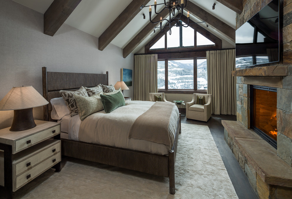 Rustikales Hauptschlafzimmer mit grauer Wandfarbe, dunklem Holzboden, Kamin und Kaminumrandung aus Stein in Sonstige