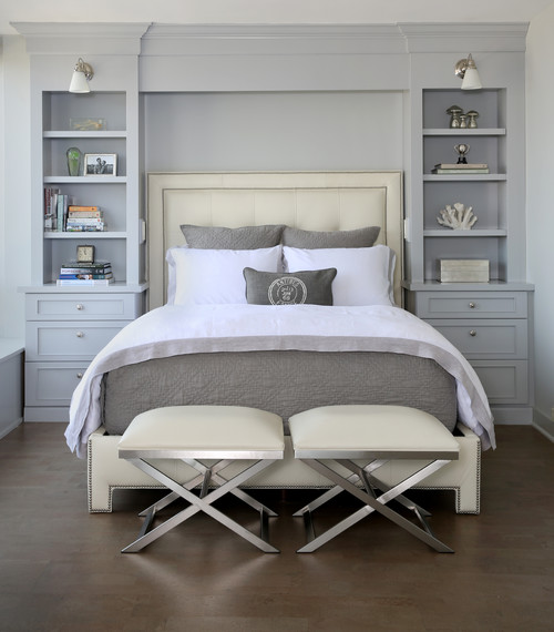 A bedroom with white bedding and soft gray furniture.
