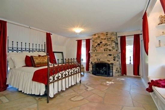 Foto di un'ampia camera matrimoniale chic con pareti beige, pavimento in pietra calcarea, camino classico e cornice del camino in pietra