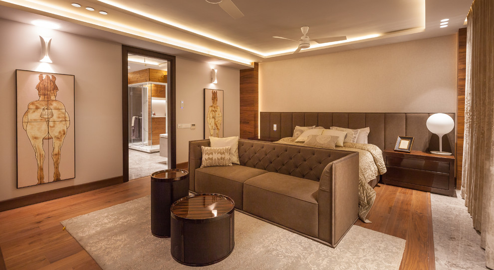 Großes Modernes Schlafzimmer mit beiger Wandfarbe und braunem Holzboden in Delhi