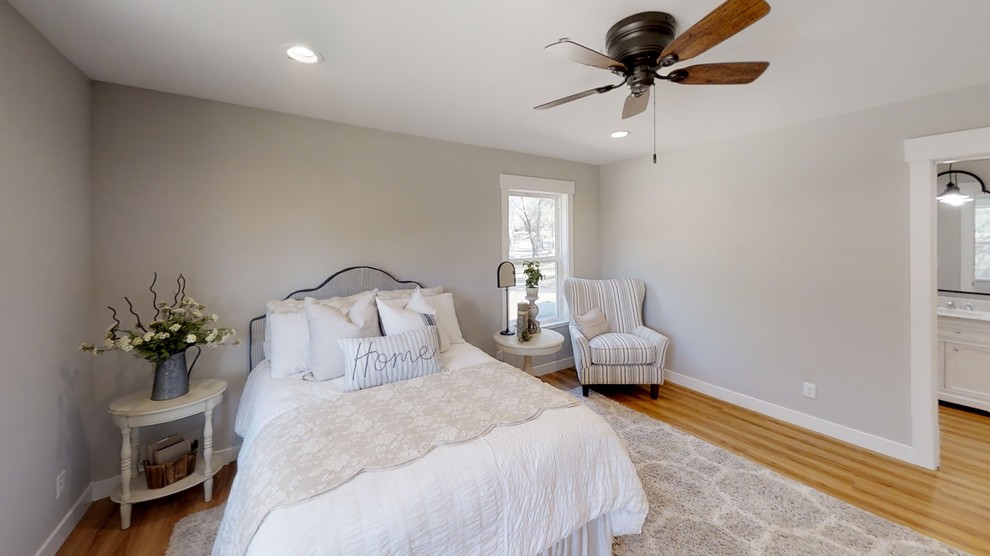 Foto de dormitorio principal campestre de tamaño medio con paredes grises, suelo laminado y suelo marrón