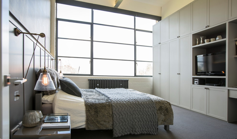 Photo of a large industrial master bedroom in London with grey walls and carpet.