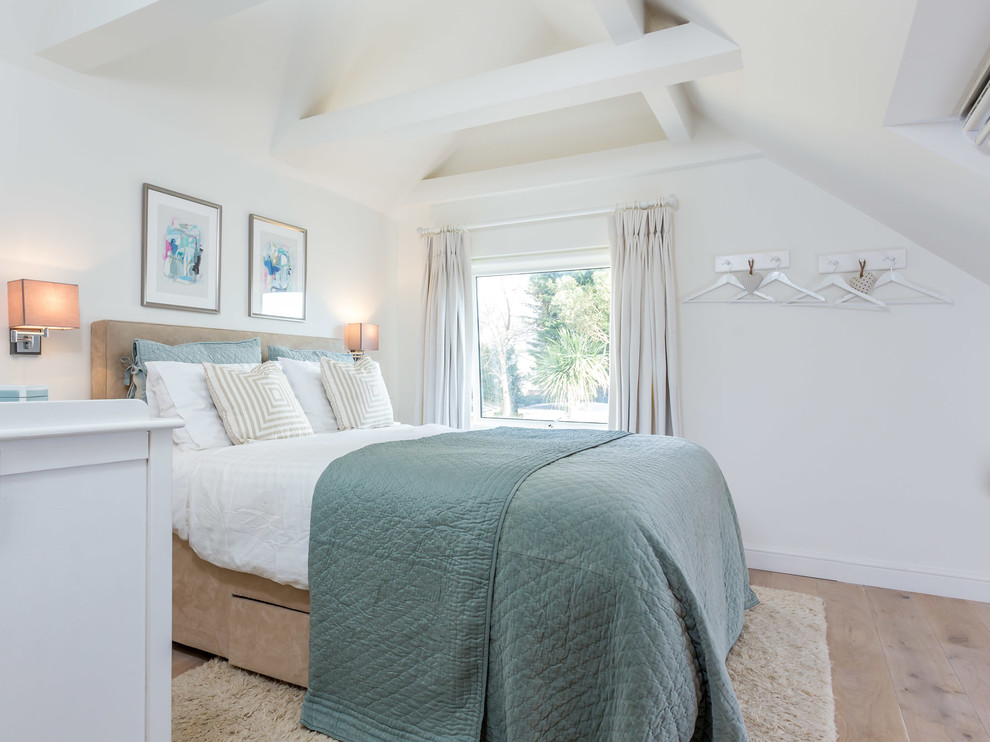 Design ideas for a medium sized beach style master bedroom in Dorset with white walls and medium hardwood flooring.