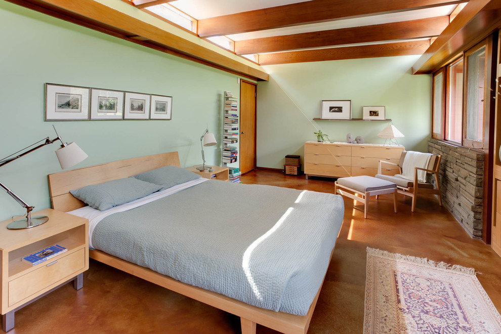Immagine di una camera da letto minimalista con pareti verdi, pavimento in cemento e nessun camino