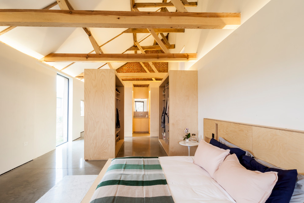Mittelgroßes Country Schlafzimmer ohne Kamin mit weißer Wandfarbe, Betonboden und grauem Boden in London