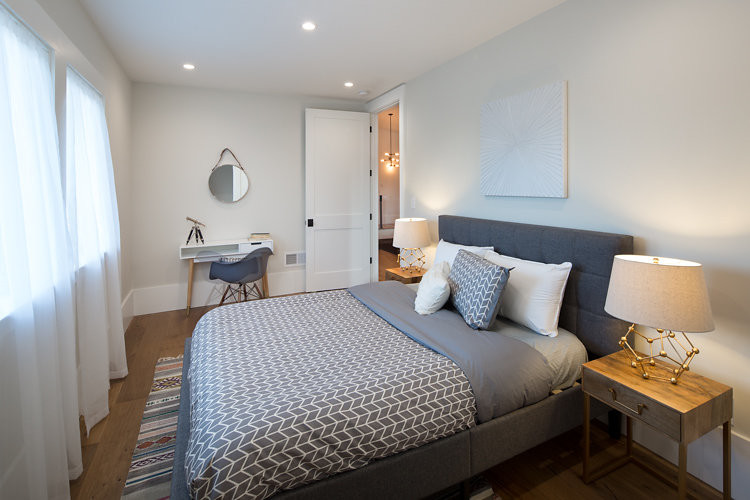 Imagen de habitación de invitados urbana de tamaño medio sin chimenea con paredes blancas y suelo de madera en tonos medios