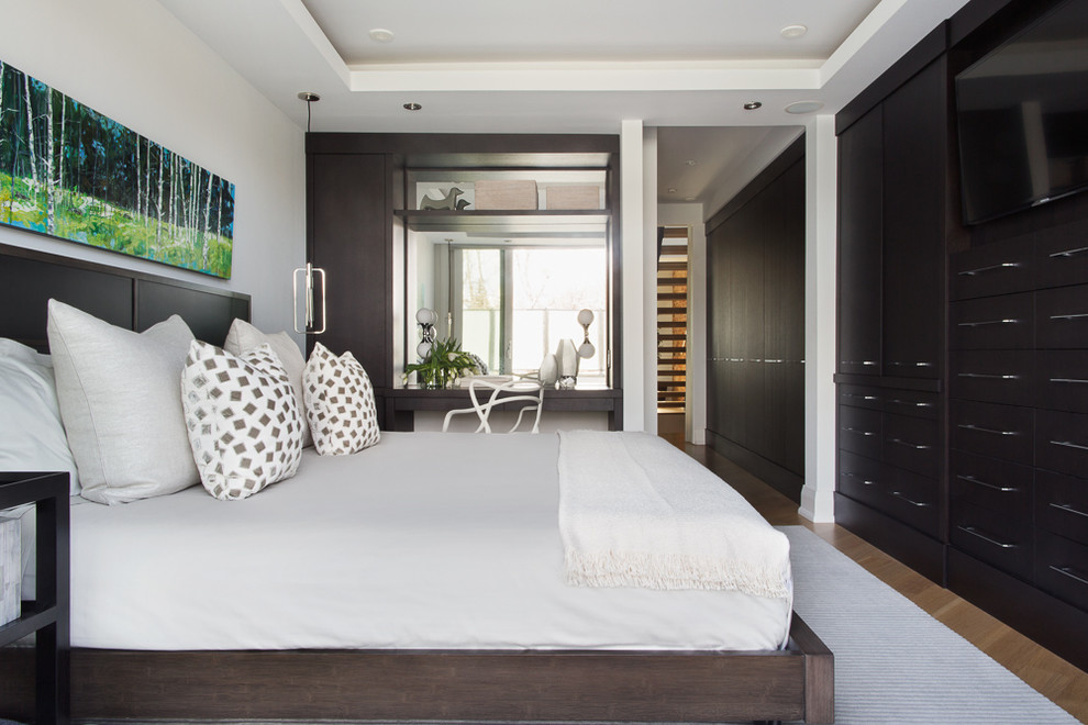 Ejemplo de dormitorio principal actual pequeño sin chimenea con paredes blancas, suelo de madera clara y suelo marrón