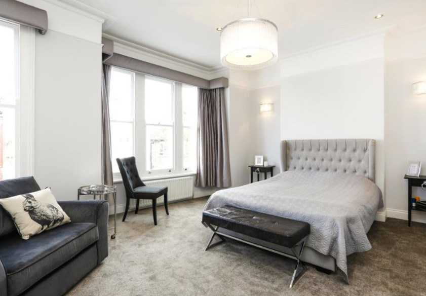 This is an example of a large traditional master bedroom in London with grey walls and carpet.