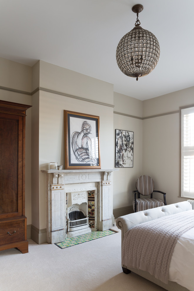 Photo of a contemporary master bedroom in London with beige walls, carpet and a standard fireplace.