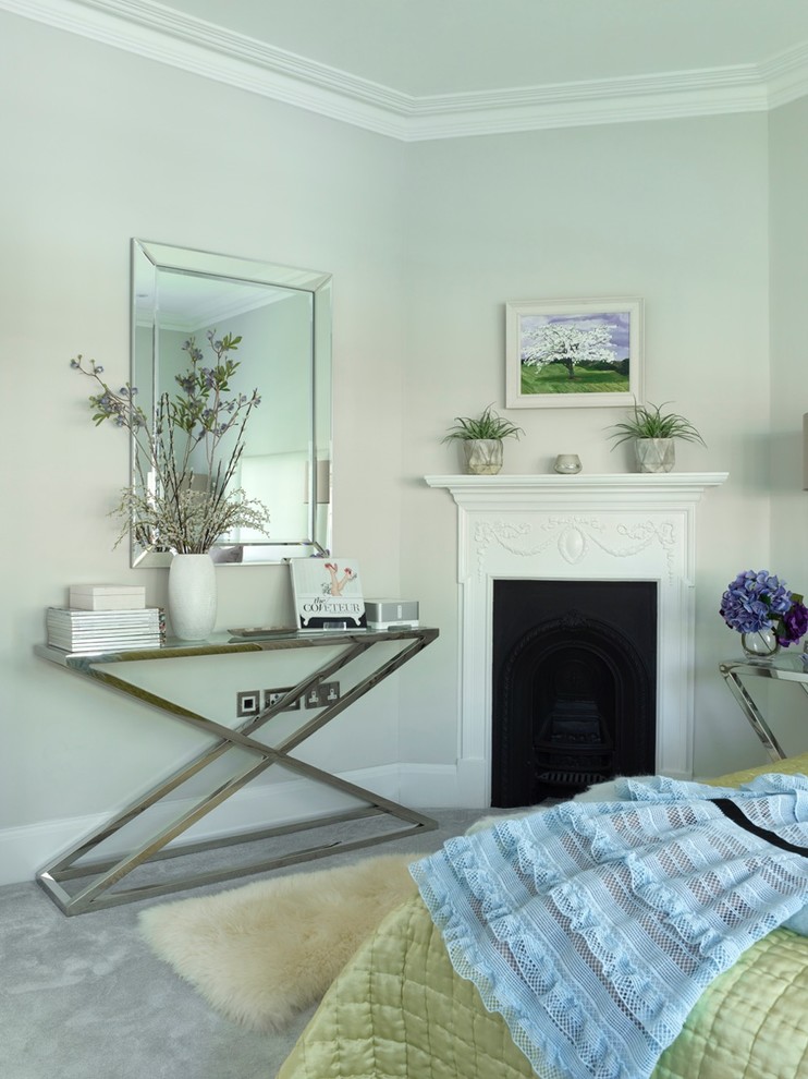 This is an example of a medium sized modern guest bedroom in London with grey walls, carpet, a standard fireplace, a metal fireplace surround and grey floors.