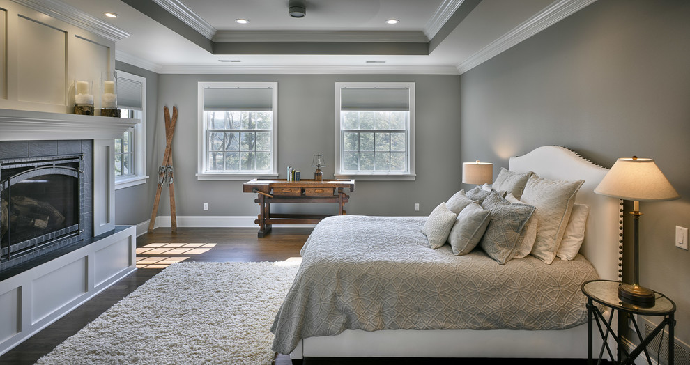 Стильный дизайн: хозяйская спальня в стиле неоклассика (современная классика) с серыми стенами, паркетным полом среднего тона, стандартным камином, фасадом камина из плитки и коричневым полом - последний тренд