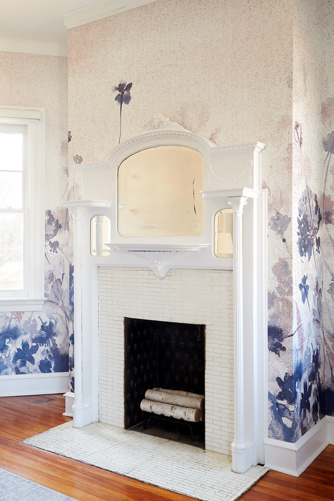 Exemple d'une chambre parentale éclectique de taille moyenne avec un mur multicolore, un sol en bois brun, une cheminée standard, un manteau de cheminée en carrelage, un sol marron et du papier peint.