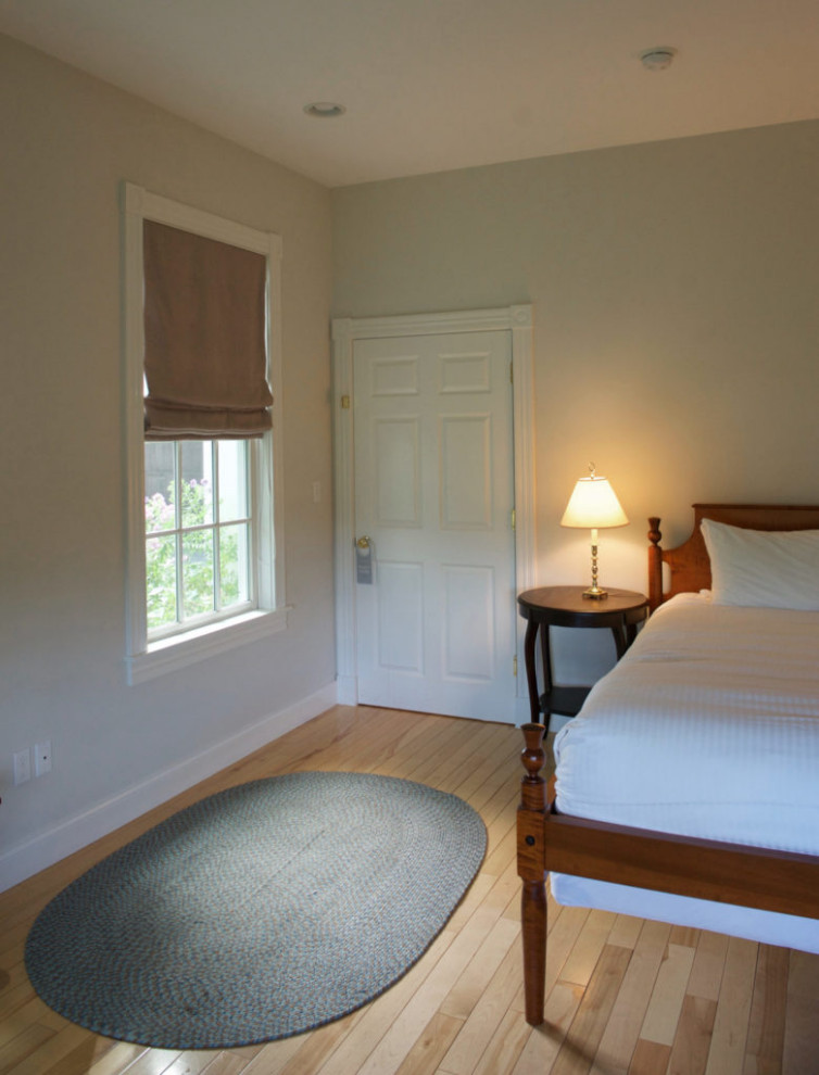 Diseño de dormitorio principal tradicional grande sin chimenea con paredes blancas, suelo de madera clara y suelo beige