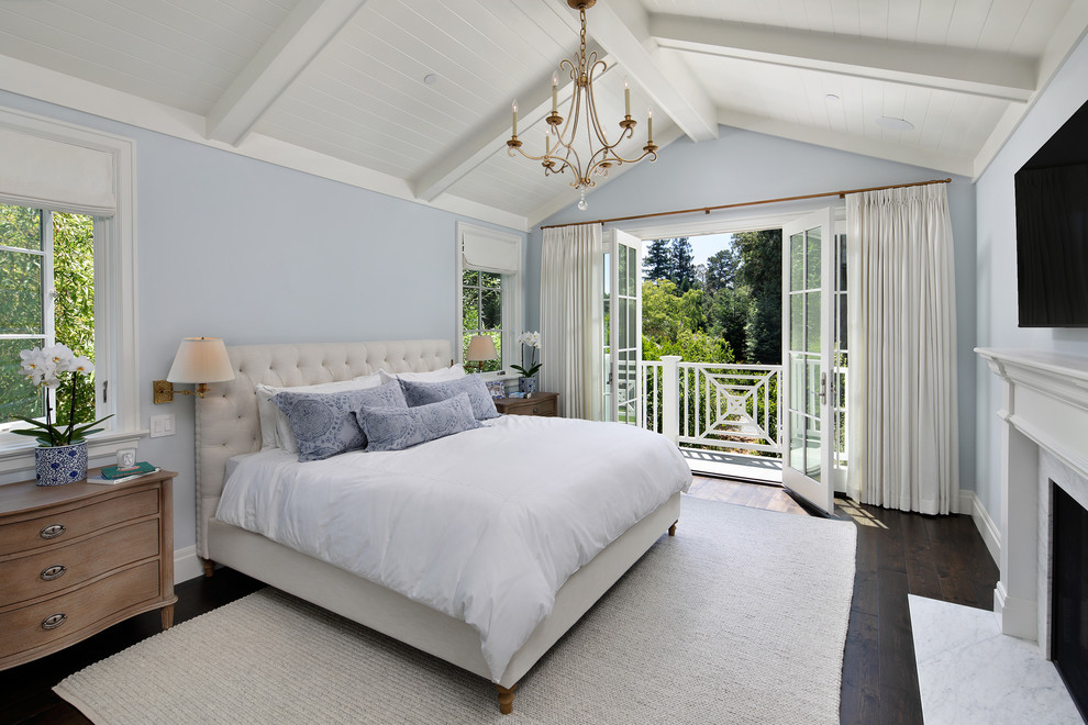 Ispirazione per una camera da letto tradizionale con pareti blu, parquet scuro, camino classico e pavimento marrone
