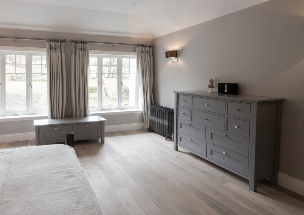 Imagen de dormitorio principal moderno grande con paredes grises y suelo de madera clara