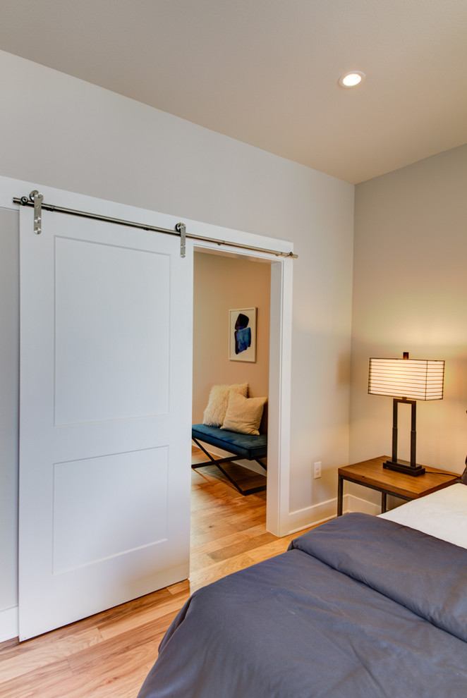 Ejemplo de dormitorio principal actual de tamaño medio con paredes grises, suelo de madera clara y suelo marrón