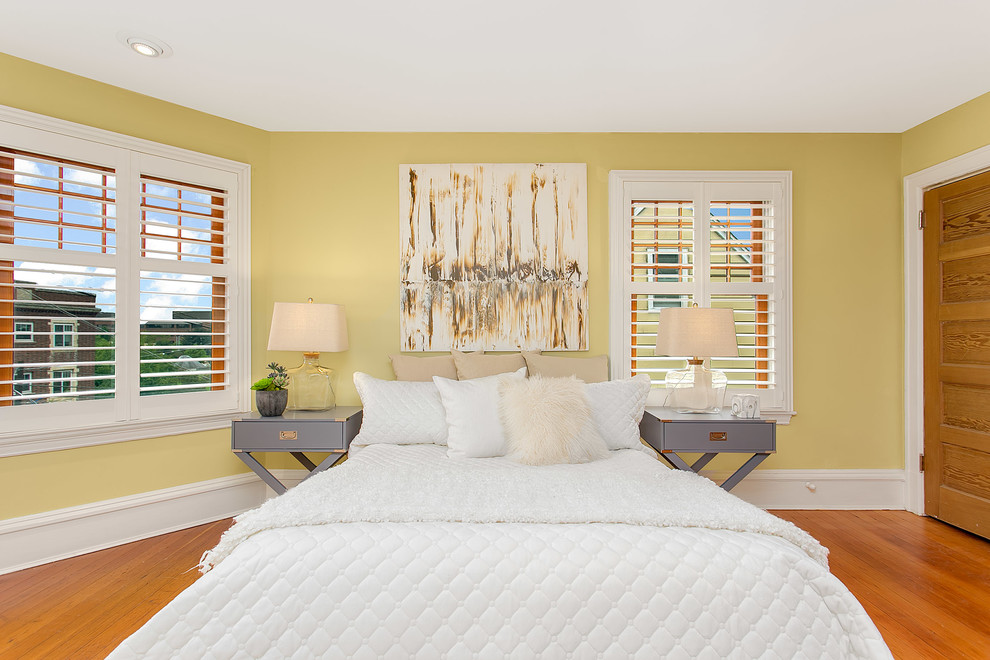 Immagine di una grande camera degli ospiti minimalista con pareti gialle e parquet chiaro